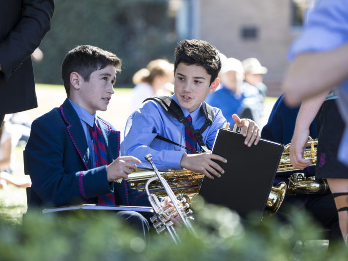 Music students sitting and talking outside holding instruments