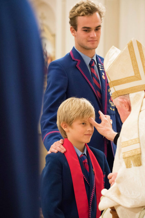 boy having the sign of the cross made on forehead