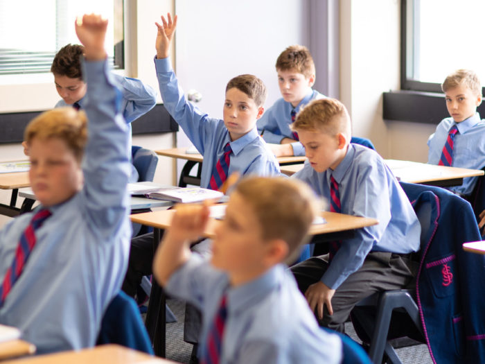 boys putting their hands up in class